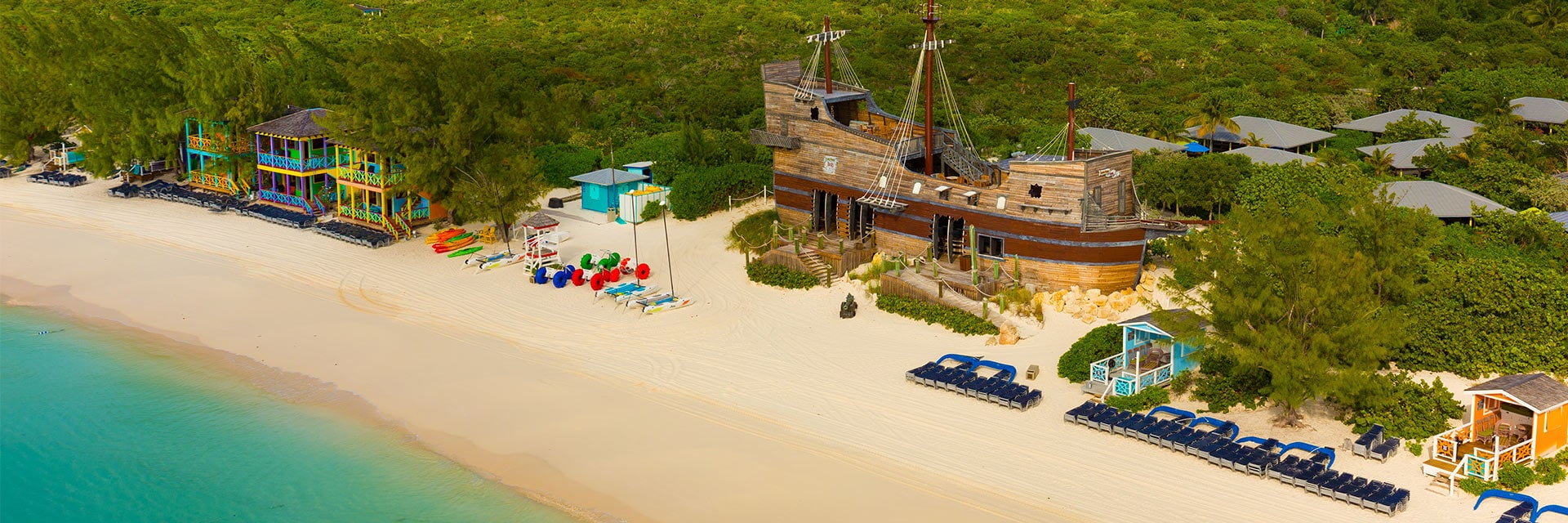 the shores of half moon cay lined with colorful buildings and a boat