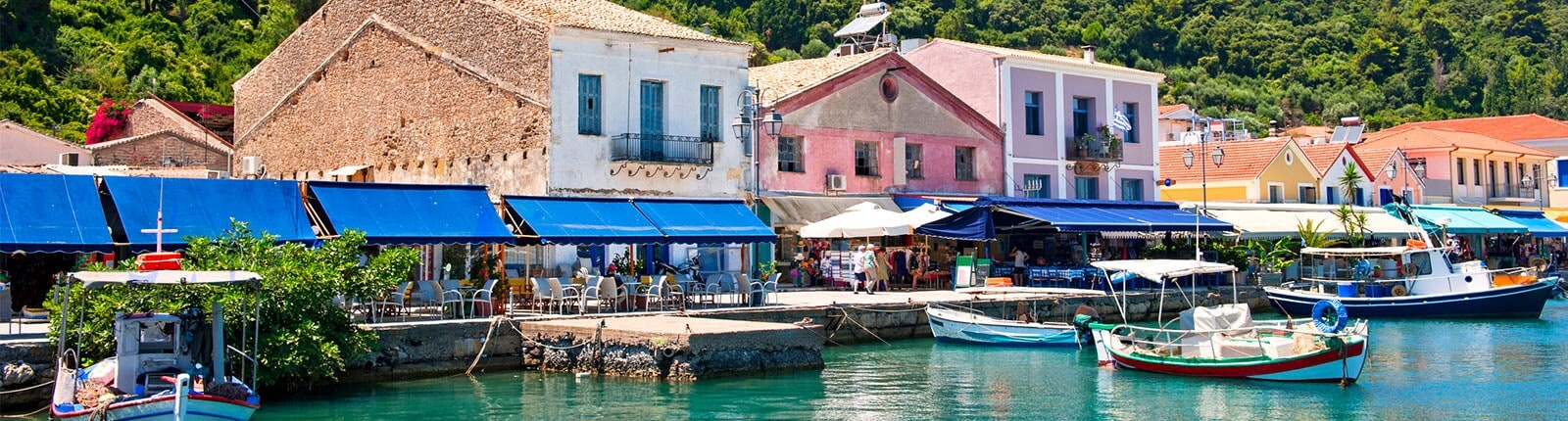 colorful boats and shops line the pier in katakolon, greece