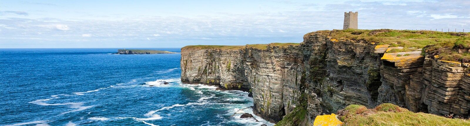 fort overlooking blue waters and large cliffs in kirkwall, orkney islands, scotland