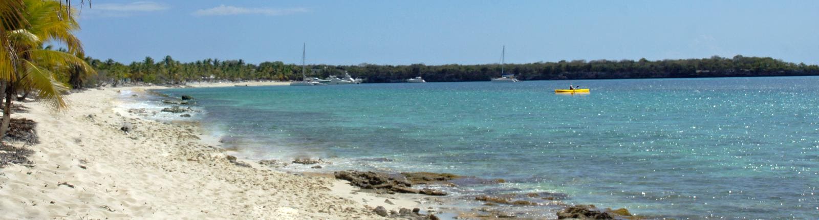 View of a beach during the day with a Kayak visible in the distance