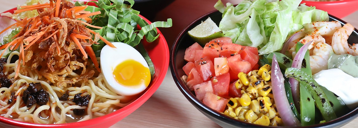 two bowls are full of food such as an egg, noodles and corn