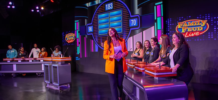 game show host speaking with contestants on family feud live