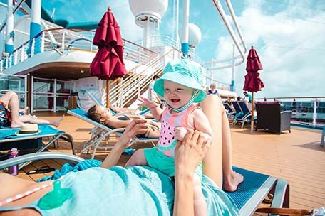 Mother and daughter sitting on a lounge chair on the deck on Carnival Vista
