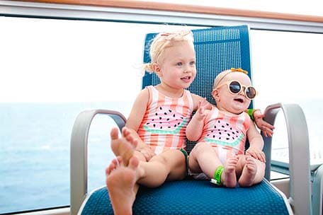 Two young girls sitting in a chair and smiling on Carnival Vista