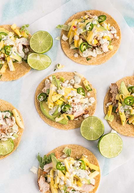 Overhead image of pineapple mango chicken tacos with limes on a table