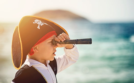 young boy in pirate costume looking through a spyglass
