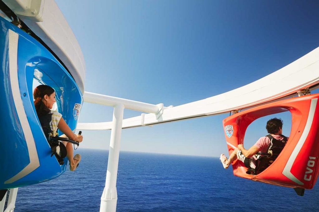 a man and woman staring at the ocean as they ride skyride on carnival horizon