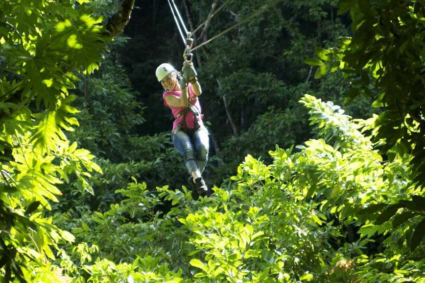 woman smiles as she zip lines over white river valley