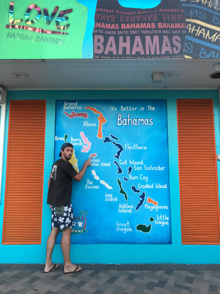 husband standing in front of Bahamas map