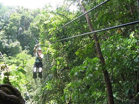 man zip lining through the veragua rainforest