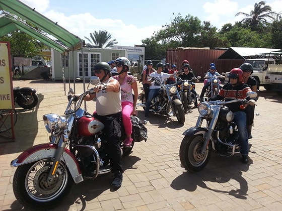 several pairs of people going on a tour of Bonaire on Harley Davidson motorcycles