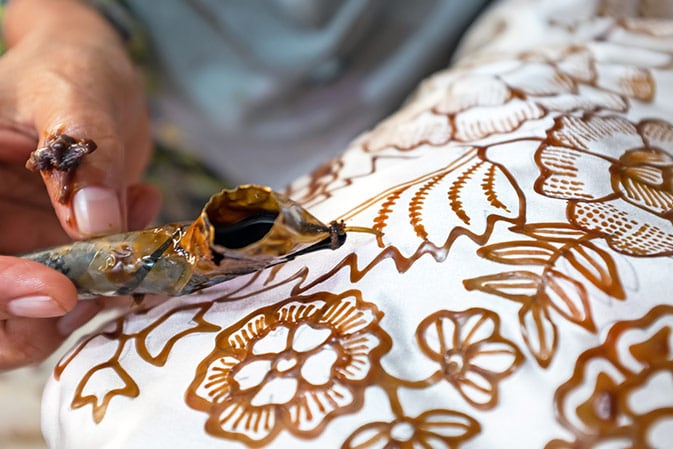 artist creating batiks from a white cloth