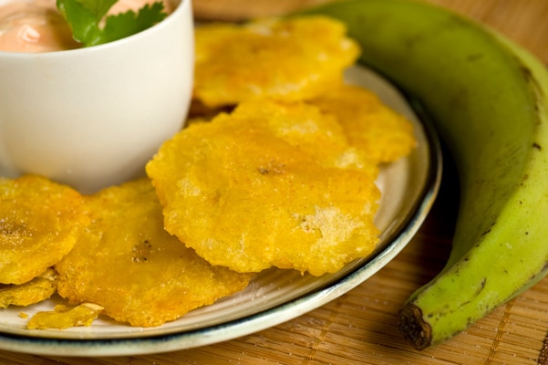 tostones served with pink sauce, next to a plantain