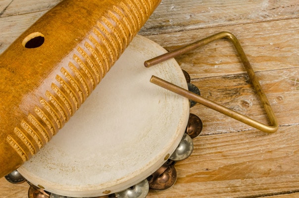 wooden guiro, tambourine, and musical triangle on a table