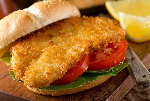 fried codfish sandwich made with tomatoes and lettuce