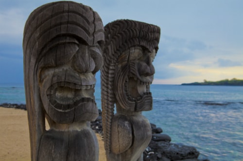 2 hawaiian totem poles looking out towards the pacific ocean 