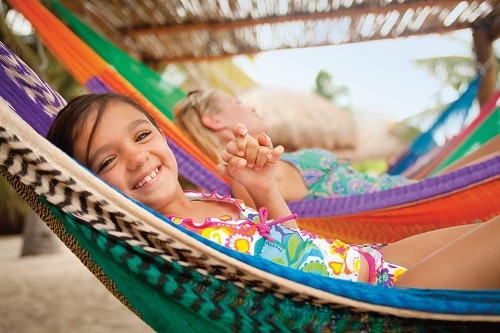 little girl smiling as she relaxes on a hammock in cozumel 
