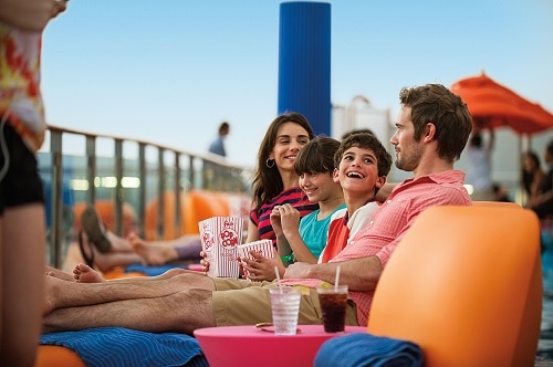 family relaxing on the ship deck as they watch a movie on the seaside theater 
