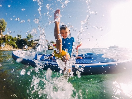 little boy on a paddle board splashing water in a caribbean private island 