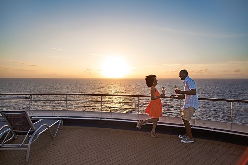couple dancing on the deck of a carnival ship as the sun sets