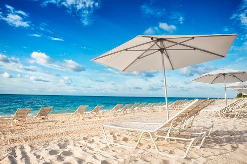 white umbrella and beach chairs on the beautiful sand of lucaya beach in freeport bahamas
