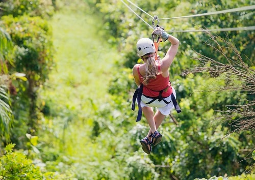 woman zip lining through the canopies of mahogany bay 