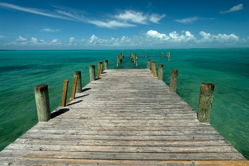 rustic wooden pier along the beautiful beach of princess cays, bahamas