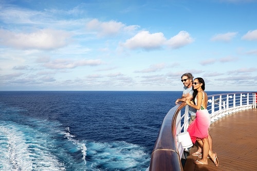 couple looking over the rail of a carnival cruise ship as they cruise ...