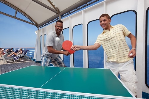 father and son playing ping pong onboard a carnival ship