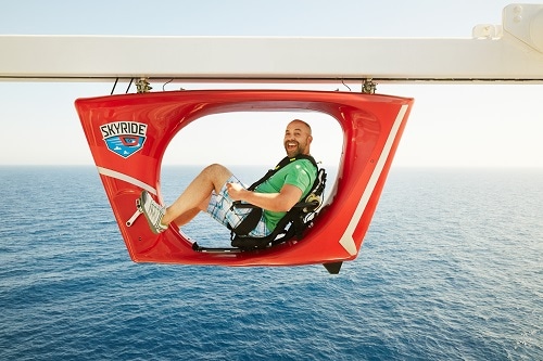 man smiling as he rides on carnival’s skyride