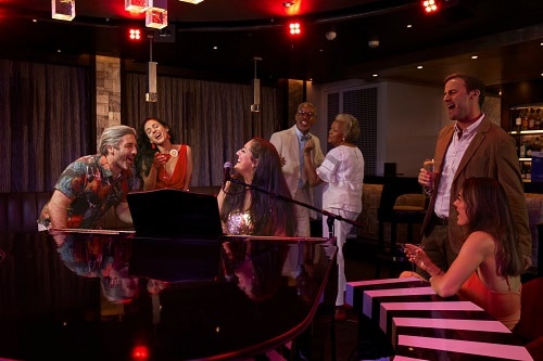 guests singing along with the pianist at the piano bar on carnival paradise