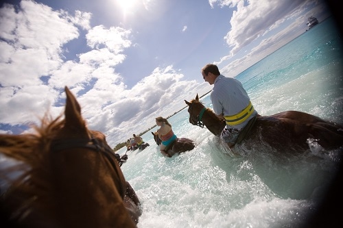 group of guests horseback riding along the shore