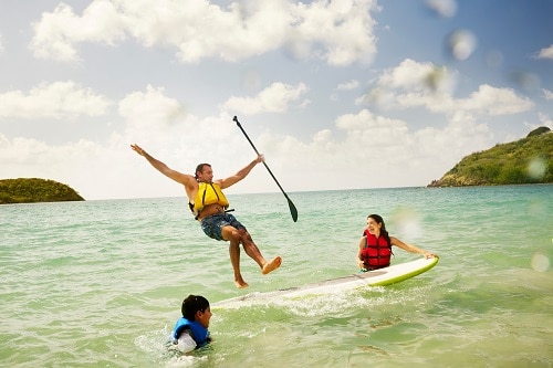 man in the Caribbean, falling off a paddle board as his family watches 