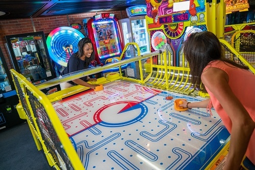 friends playing air hockey at the video arcade on board carnival elation 
