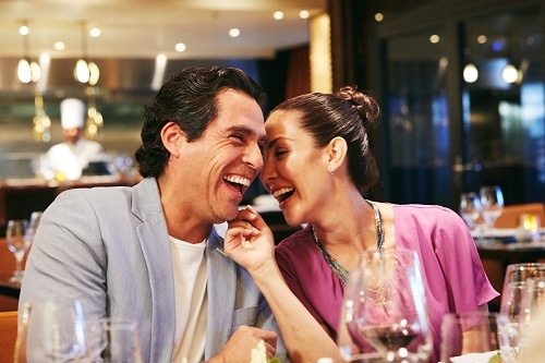 well-dressed couple laughing during dinner onboard a carnival ship