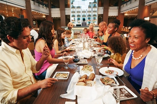 two families eating dinner together on a carnival ship