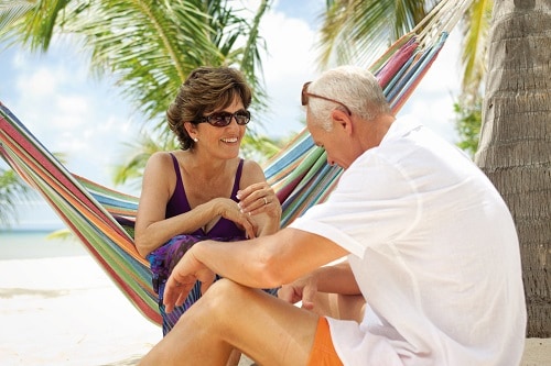 senior couple sitting on a hammock on the beach