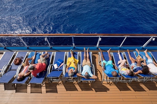 row of people sitting in chairs near the railing of a carnival ship