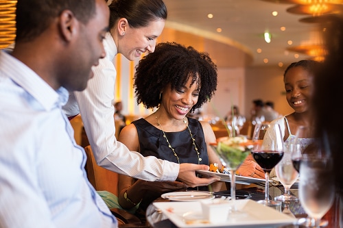 waitress serving guests their food onboard carnival’s steakhouse