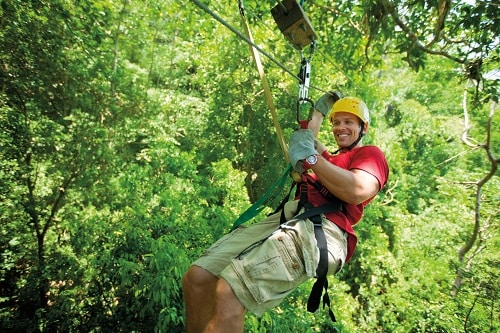 a man zip lining through the forest
