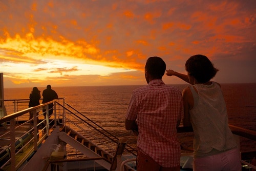 couple looking out to the sunset onboard a carnival ship