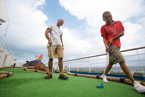father and son playing mini golf onboard a carnival ship