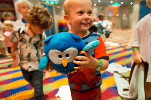 little boy happily holding a plush blue owl