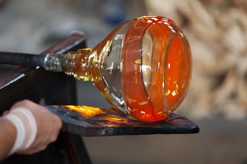 a glassblower crafting a bottle in italy