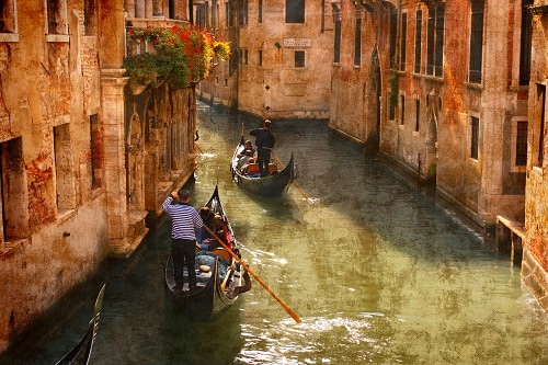 two gondoliers paddling their gondolas through the water road