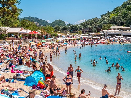 a beach full of travelers at paleokastritsa in corfu