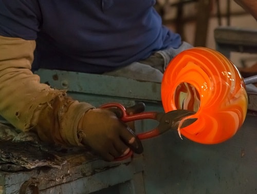 a glass blower finishing their glass sculpture