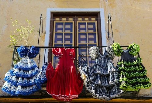 four flamenco dresses hanging from a balcony in malaga