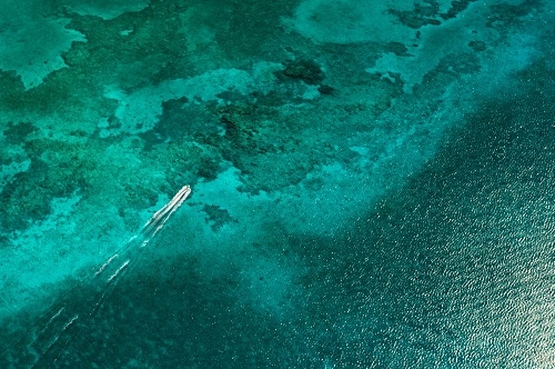 aerial view of a boat on the sea green waters of grand cayman