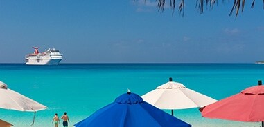 Beach With Umbrellas And Carnival Cruise Ship In The Ocean